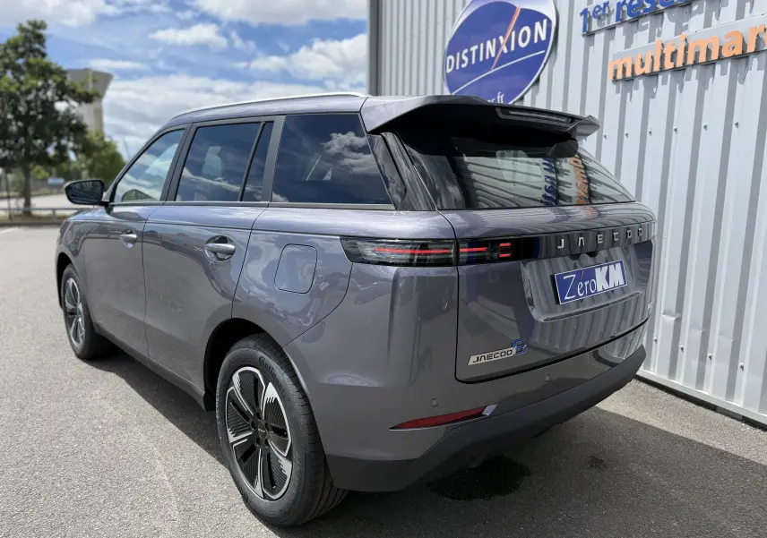 Vue 3/4 arrière droite du JAECOO J5 gris Phantom avec feux arrière étirés et jantes noires bicolores.