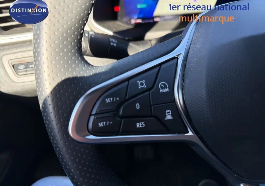 Gros plan sur les commandes au volant perforé noir du Renault Symbioz 2025, version hybride gris Rafale métal.