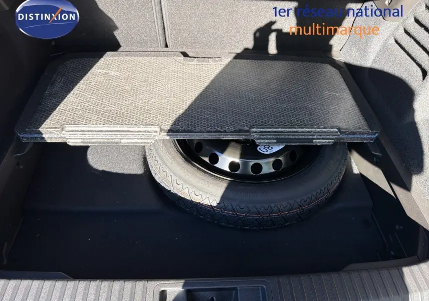 Vue du coffre ouvert de la Renault Symbioz gris Rafale métal, montrant la roue de secours sous la tablette amovible.