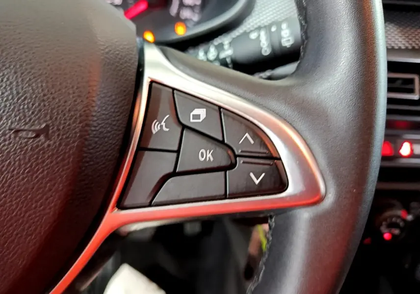 Gros plan sur les commandes multifonctions à droite du volant cuir synthétique de la Dacia Sandero Confort TCe 90 blanche 2022.