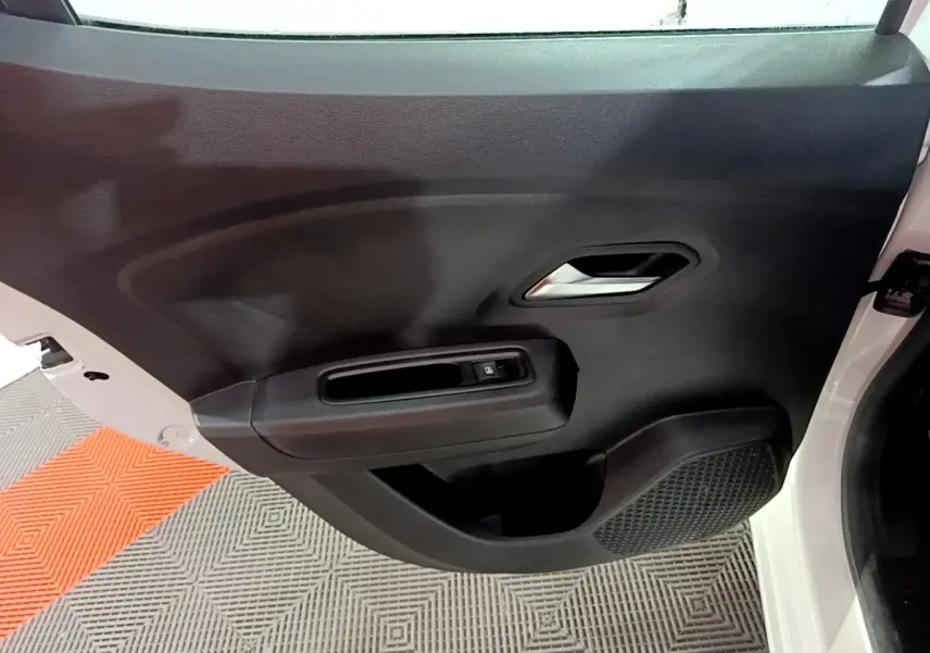 Vue rapprochée de la porte arrière droite noire d'une Dacia Sandero blanche 2022, avec poignée et commande de vitre électrique.