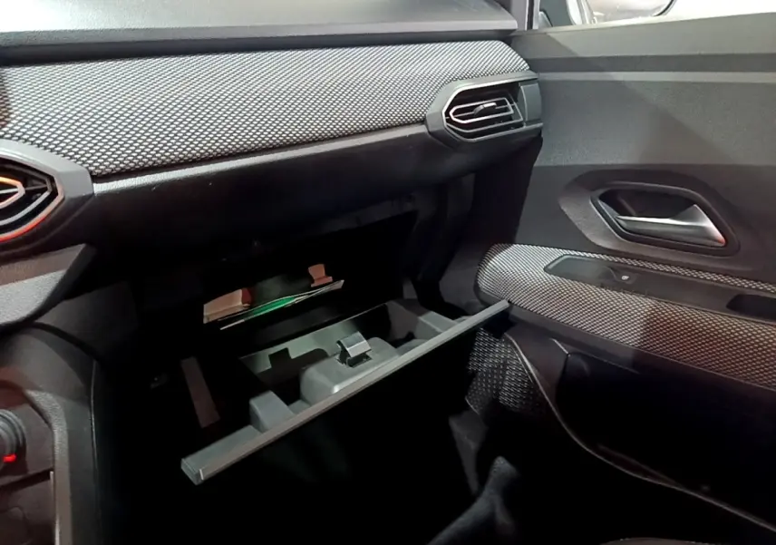 Intérieur de la Dacia Sandero Confort TCe 90 2022, vue côté passager avec boîte à gants ouverte et garnitures texturées noires.