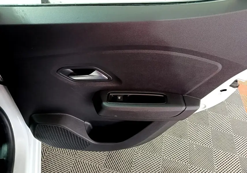 Vue rapprochée de la porte avant gauche noire d'une Dacia Sandero blanc 2022, avec poignée et commande de vitre électrique.