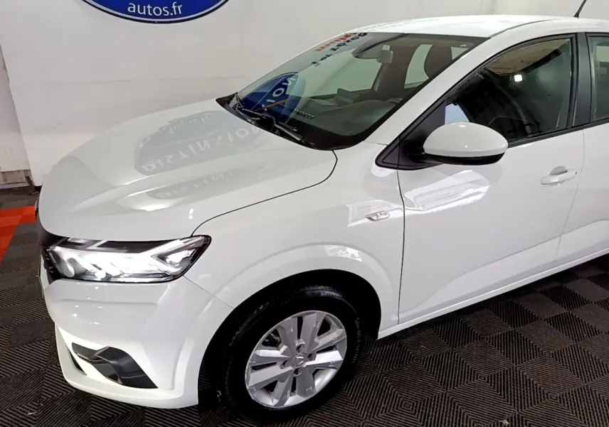 Vue 3/4 avant droite d'une Dacia Sandero blanche 2022 avec phares LED et jantes alliage visibles.