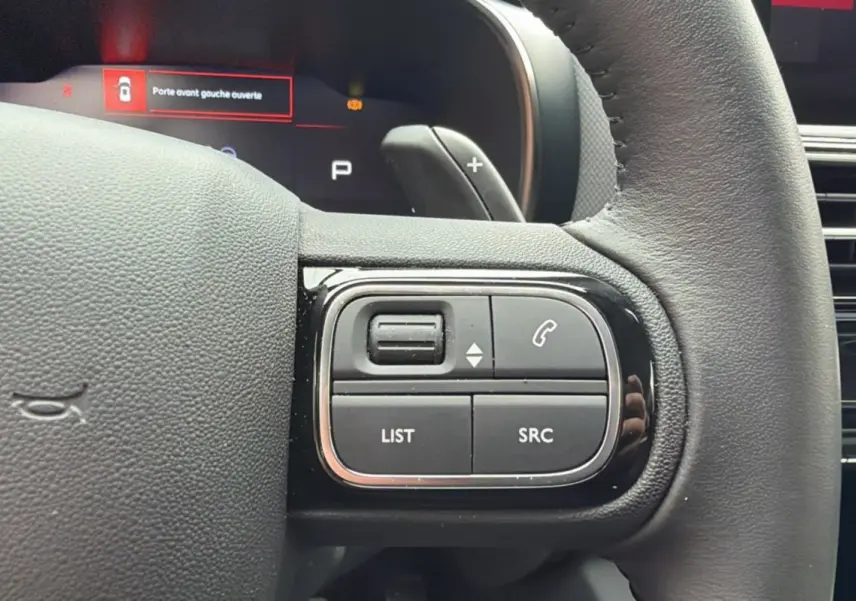 Gros plan sur les commandes multifonctions du volant cuir du Citroën C5 Aircross Hybrid 2025, finition gris platinium.