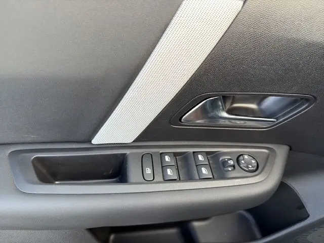 Gros plan sur la commande des vitres et rétroviseurs côté conducteur d'une Citroën C4 hybride gris clair.
