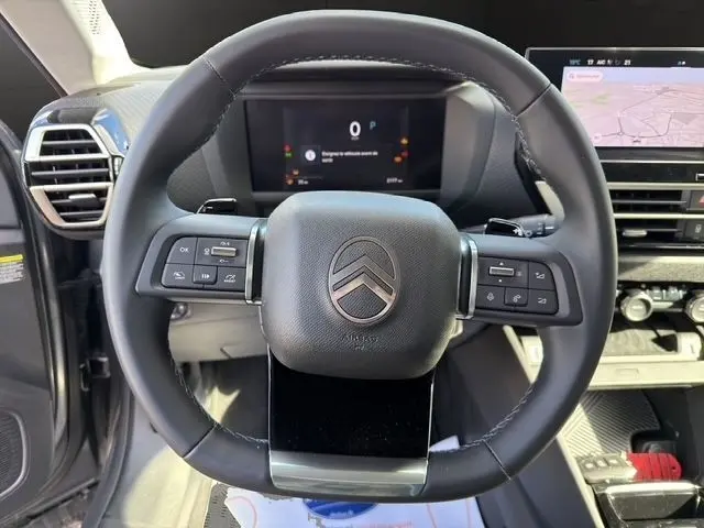 Vue frontale du volant cuir noir de la Citroën C4 hybride 2025, avec tableau de bord numérique et écran tactile central.