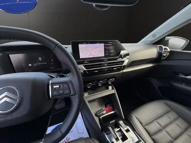 Vue intérieure avant droite du Citroën C4 hybride gris clair 2025, avec tableau de bord numérique et écran tactile central.