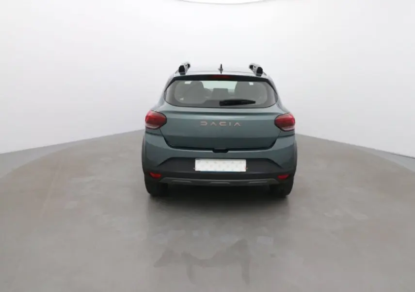 Vue arrière d'une Dacia Sandero Stepway 2025 vert cèdre, avec logo et feux arrière visibles dans un studio neutre.