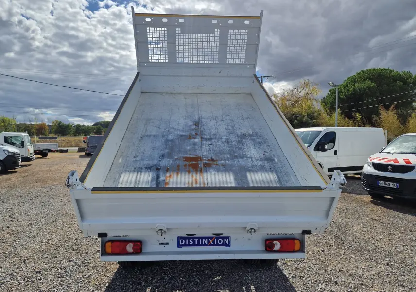 Vue arrière d’une benne blanche Renault Master Châssis Cabine 2024 avec benne relevée et plateau métallique usé.
