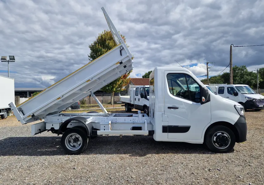 Vue de profil droit d’un Renault Master Châssis Cabine blanc avec benne basculante relevée et roues jumelées arrière.