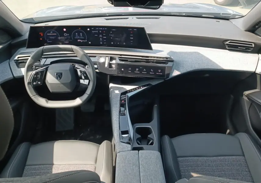 Vue intérieure avant du Peugeot 5008 Hybrid 145 allure e-dcs6 2025, tableau de bord moderne gris avec volant cuir multifonction.
