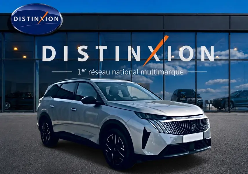 Peugeot 5008 gris artense en 3/4 avant droit, avec calandre distinctive et jantes alu noires.