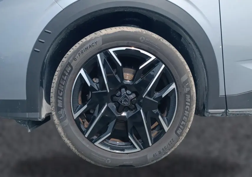 Gros plan sur la roue avant droite du Peugeot 5008 gris Artense avec jante alliage noire et inserts argentés.