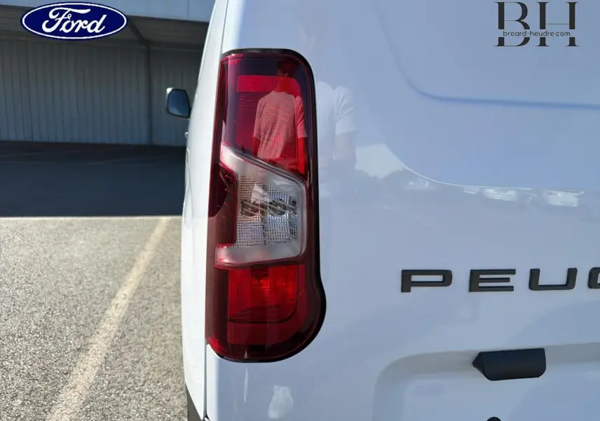 Gros plan sur le feu arrière gauche d’un Peugeot Partner blanc Icy, avec partie arrière droite du véhicule visible.