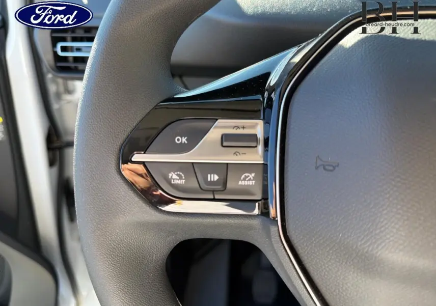 Gros plan sur le volant multifonction noir avec commandes de régulateur et limiteur de vitesse d'un véhicule Ford.