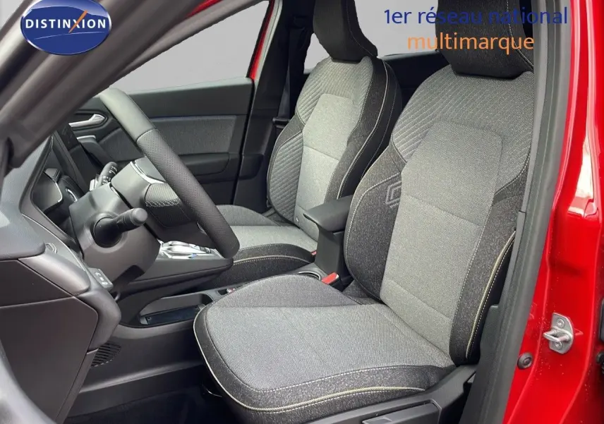 Intérieur avant du Renault Captur rouge passion 2025, sièges tissu gris avec surpiqûres contrastées et volant visible.