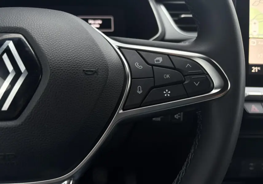 Gros plan sur la partie droite du volant noir du Renault Captur 2025 avec commandes multifonctions et écran tactile en arrière-plan.