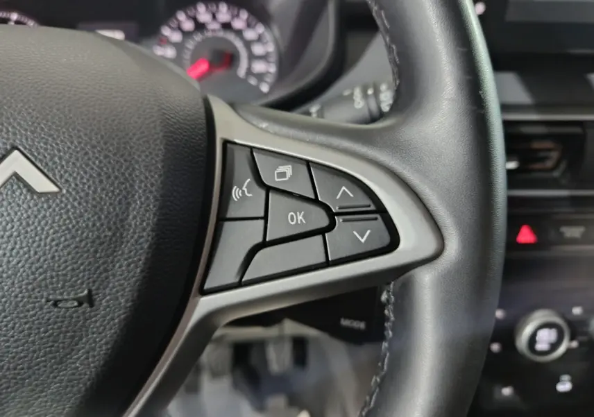 Gros plan sur le volant cuir synthétique noir de la Dacia Sandero 2024 avec commandes multifonctions côté gauche.