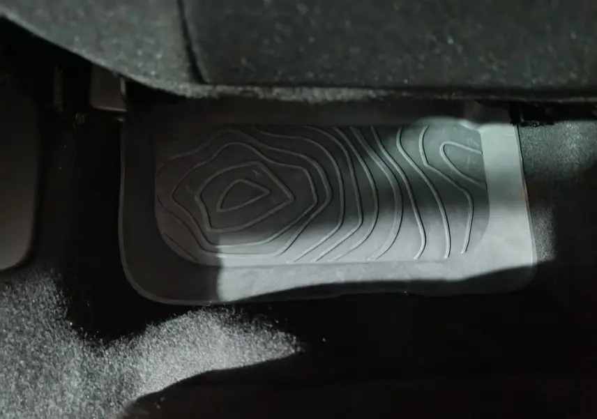 Gros plan sur le tapis de sol noir côté conducteur d'une Dacia Sandero Extreme+ bleu 2024, intérieur sombre.