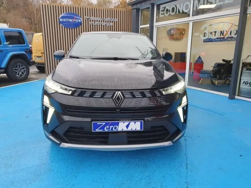 Vue avant d'une Renault SYMBIOZ 1.6 E-Tech noir étoilé avec feux LED et calandre distinctive, sur sol bleu devant un showroom.