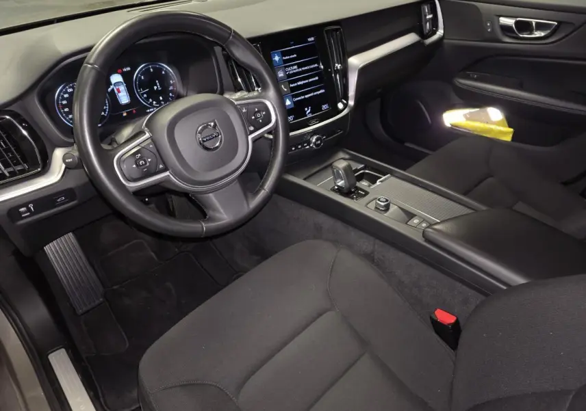 Intérieur avant droit de la Volvo V60 B4 2021, montrant le volant, tableau de bord digital et console centrale noire.