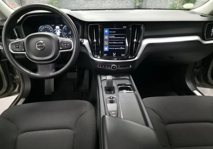 Vue intérieure avant de la Volvo V60 gris, avec tableau de bord digital et écran tactile central vertical.