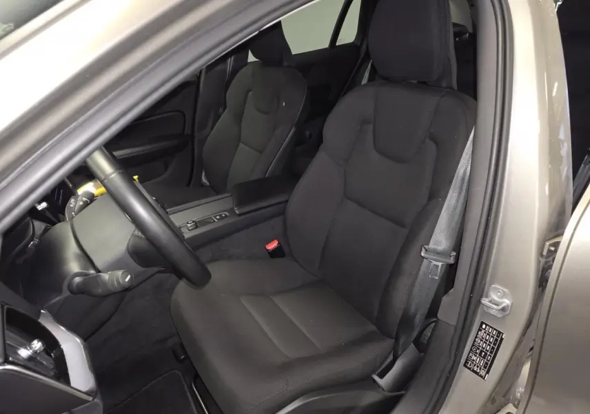 Vue intérieure côté conducteur d'une Volvo V60 gris 2021, mettant en valeur le siège textile noir et la ceinture de sécurité.