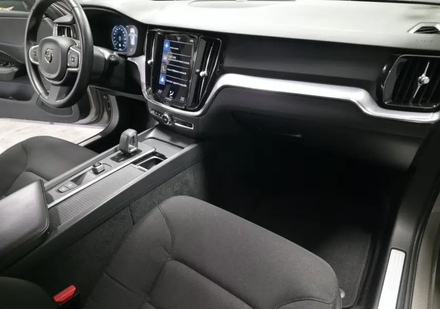 Vue intérieure côté passager du tableau de bord et console centrale noire du Volvo V60 B4 2021 avec écran tactile vertical.