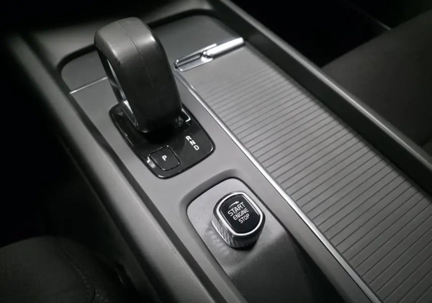 Gros plan sur la console centrale noire avec levier de vitesses automatique et bouton Start Engine Stop d'une Volvo V60.