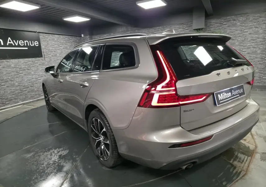 Vue 3/4 arrière droite d'un Volvo V60 gris métallisé avec feux arrière LED en forme de L et double sortie d'échappement.