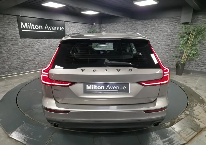 Vue arrière d'une Volvo V60 gris métallisé avec feux arrière LED en forme de L et double sortie d'échappement visible.