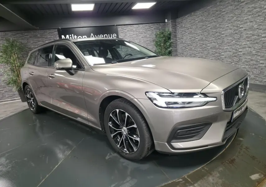 Volvo V60 B4 gris métallisé vue 3/4 avant droit avec jantes alliage noires et calandre chromée.