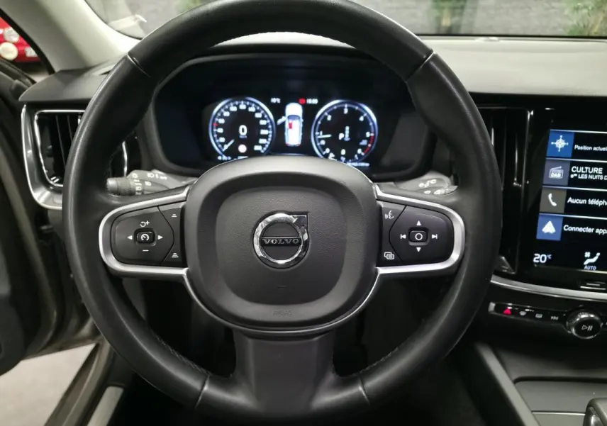 Vue intérieure centrée sur le volant noir de la Volvo V60 2021 avec tableau de bord digital et écran tactile.