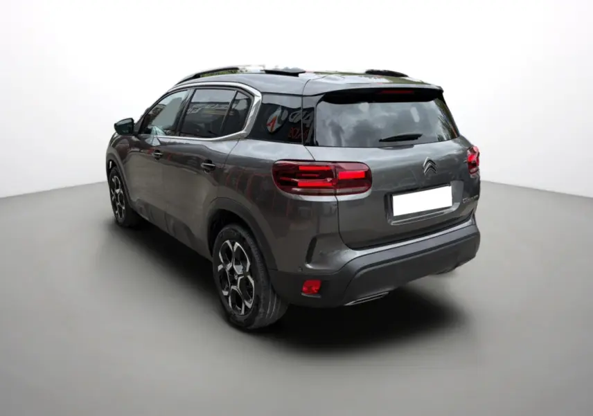 Vue 3/4 arrière gauche d'un Citroën C5 Aircross Hybrid 145 gris platinium avec barres de toit et vitres surteintées.