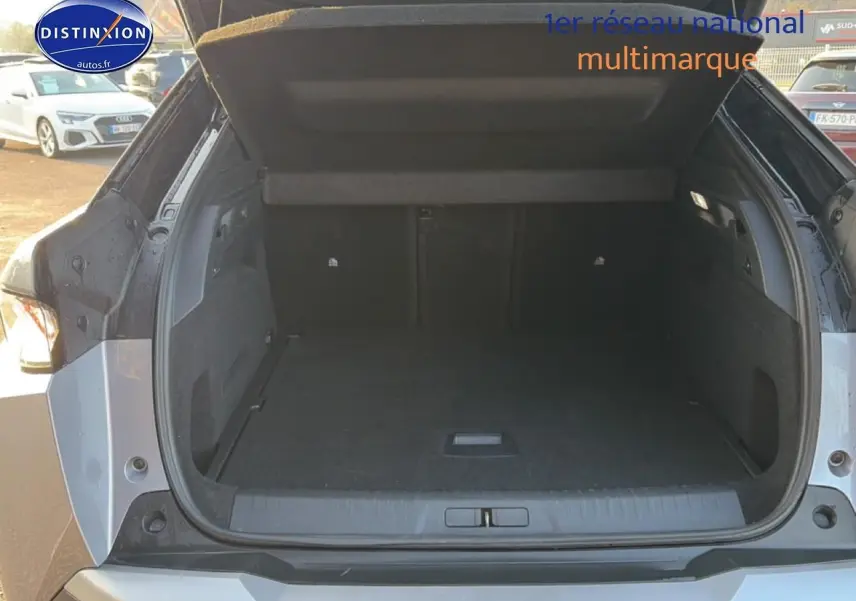 Coffre ouvert d’un Peugeot 3008 gris vu de l’arrière, montrant l’espace de chargement vide et la trappe de plancher.