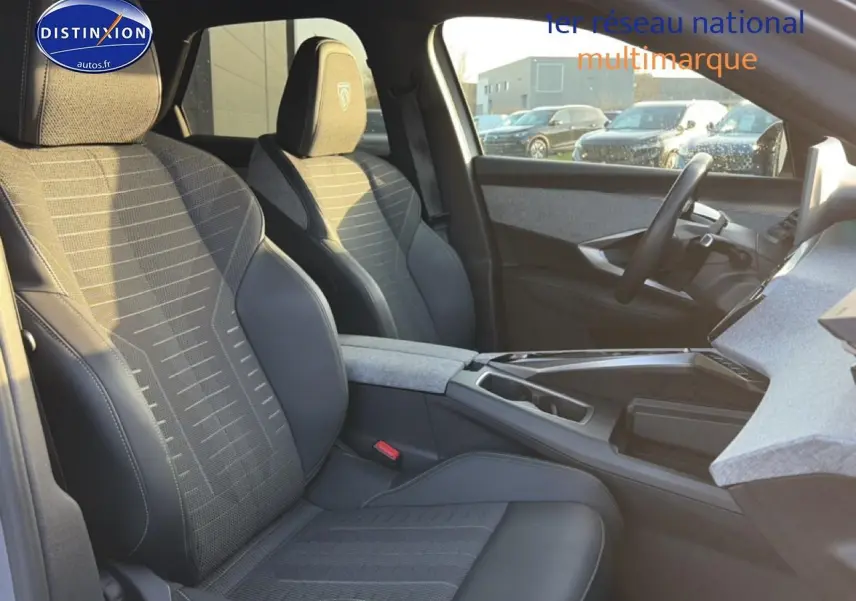 Vue intérieure côté conducteur du Peugeot 3008 gris 2025, sièges tissu et cuir avec accoudoir central.