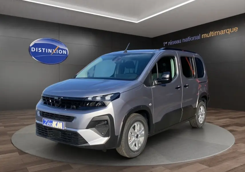 Peugeot Rifter gris clair en 3/4 avant droit, avec calandre noire et jantes argentées en showroom.