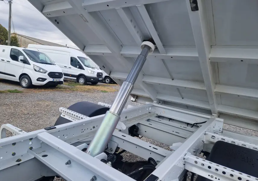 Gros plan sur le système hydraulique de la benne relevée du Renault Master Châssis Cabine blanc, vue arrière côté droit.