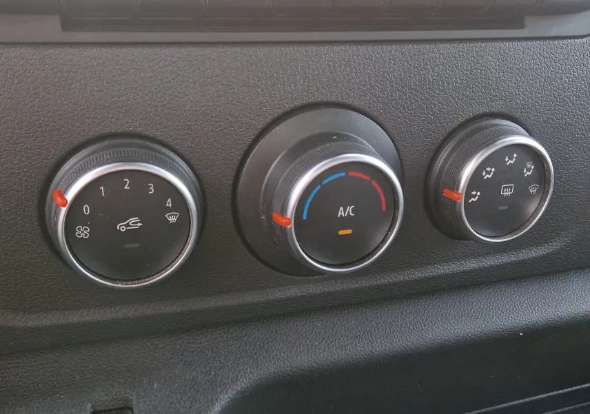 Gros plan sur les commandes de climatisation du Renault Master Châssis Cabine blanc, avec boutons rotatifs noirs et marquages blancs.