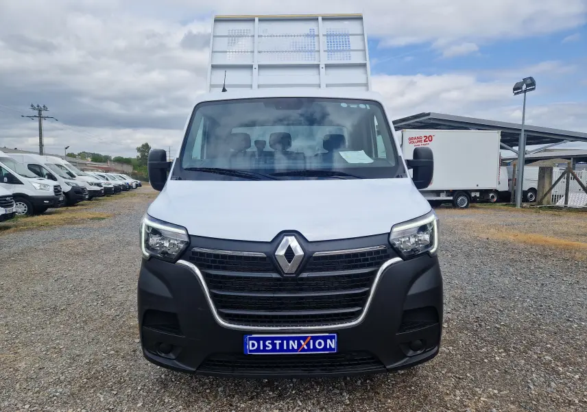 Vue frontale d’un Renault Master Châssis Cabine blanc avec benne haute et calandre noire, stationné sur un sol gravillonné.