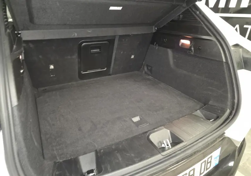 Vue intérieure du coffre ouvert de l'Alfa Romeo Tonale blanc, montrant un espace de chargement propre et bien éclairé.