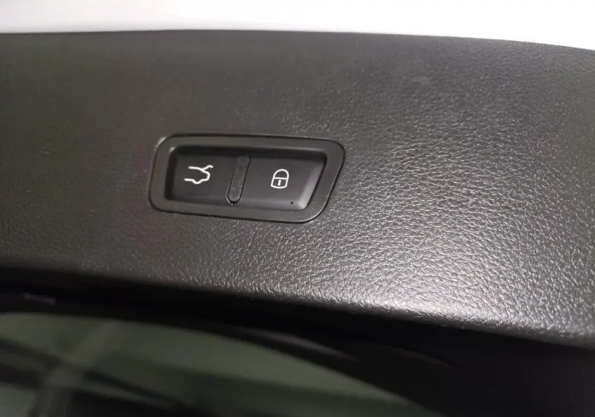 Gros plan sur les boutons d'ouverture du hayon électrique et de verrouillage, sur la garniture intérieure noire.
