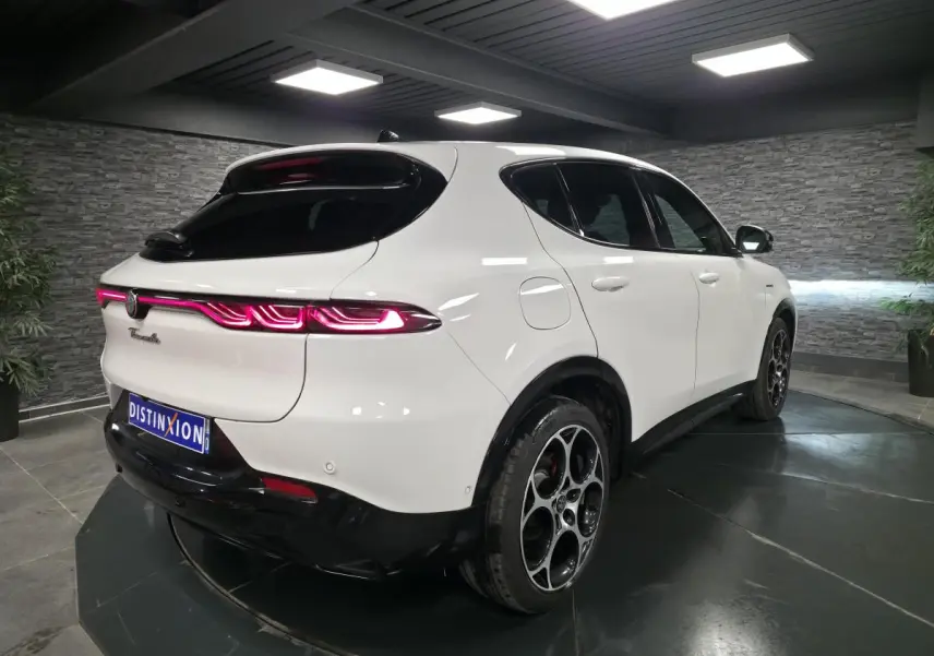 Vue 3/4 arrière droite d'une Alfa Romeo Tonale blanche avec feux arrière LED et jantes alliage noires et argent.