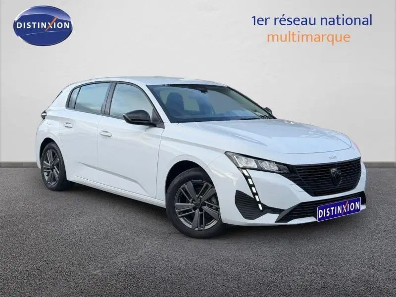 Peugeot 308 blanc Okénite vue 3/4 avant droit, avec calandre noire et feux LED verticaux distinctifs.