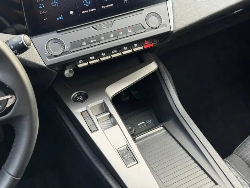 Vue intérieure centrée sur la console centrale de la Peugeot 308 2024 blanche, avec commandes tactiles et bouton start/stop.