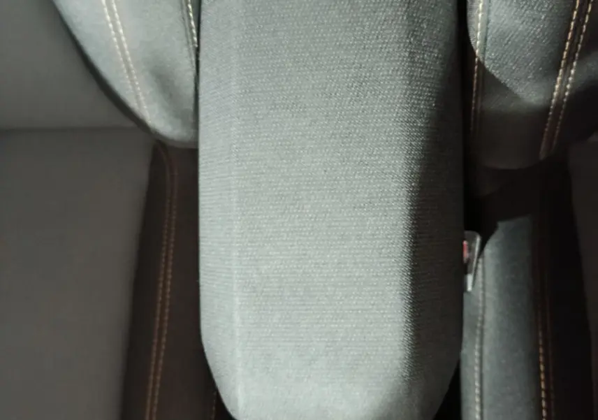 Vue plongeante sur l'accoudoir central tissu gris entre les sièges avant du Dacia Sandero Extreme+ 2024.