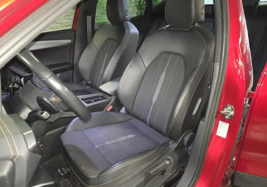 Vue intérieure côté conducteur du CUPRA Formentor rouge 2022, sièges sport noirs avec surpiqûres cuivre.