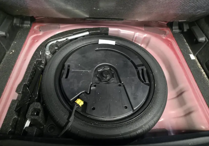 Vue rapprochée du coffre ouvert du CUPRA Formentor rouge 2022, montrant la roue de secours compacte et ses outils.