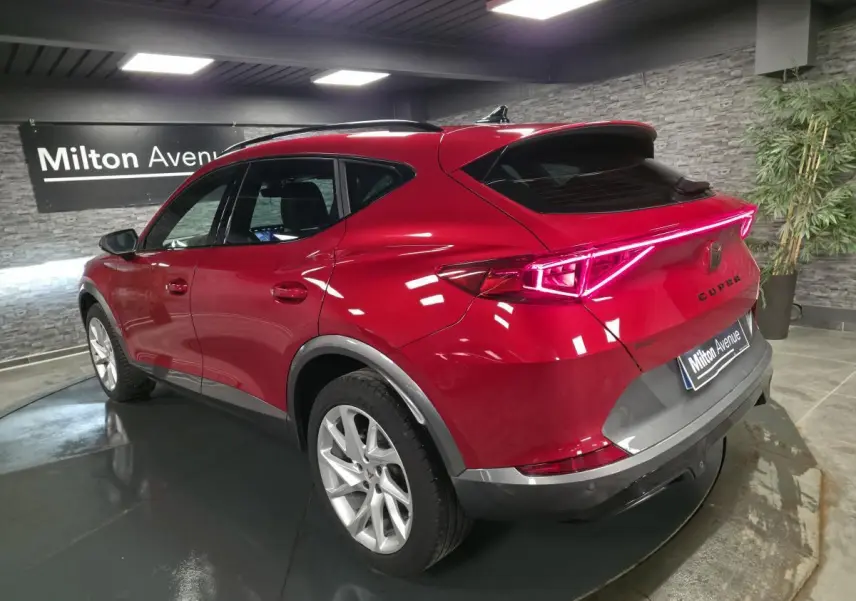 Vue 3/4 arrière droite du CUPRA Formentor rouge avec bandeau lumineux LED et jantes alliage 18 pouces.